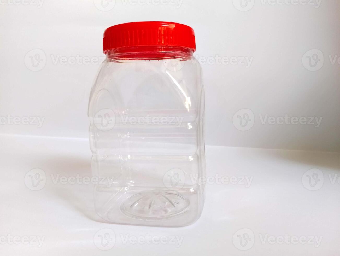 A empty transparint bttle with rad cap on a white background. photo