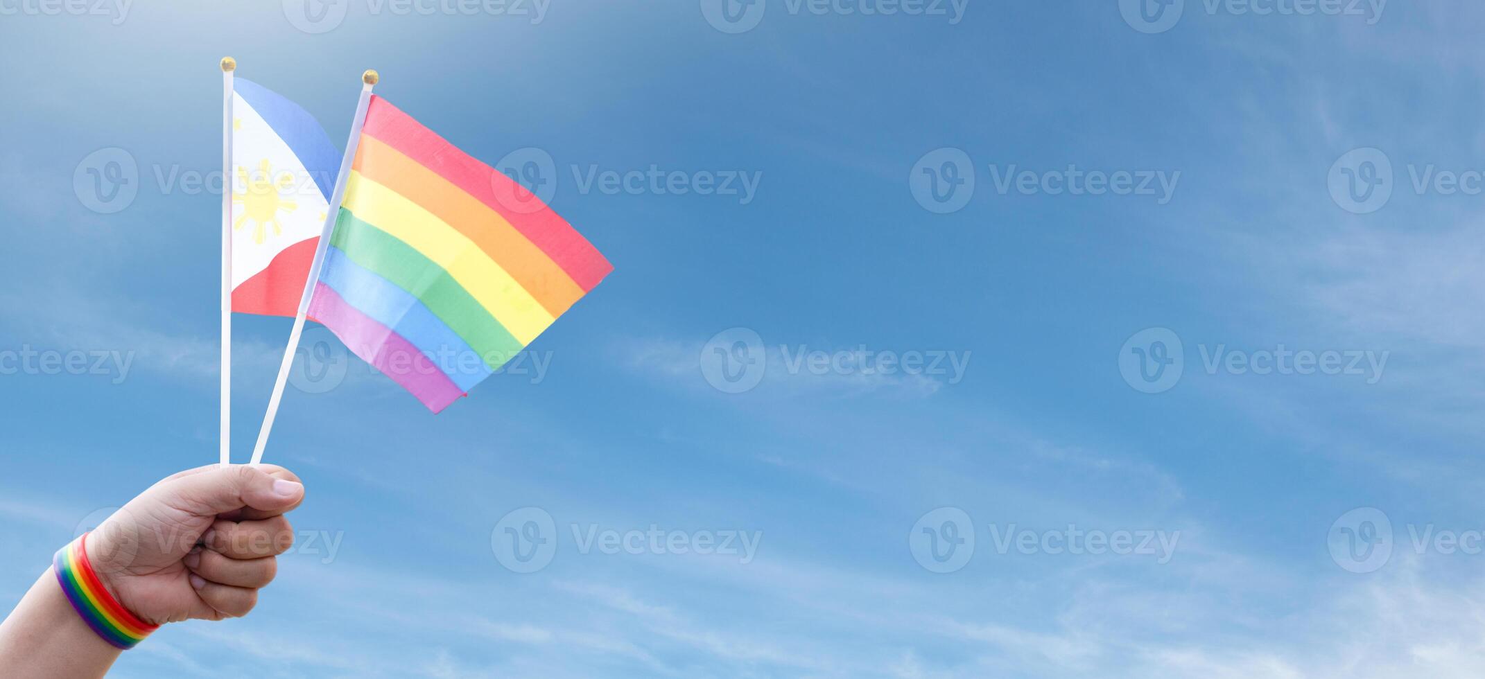 Rainbow flags and Philipines flag showing in hands against clear bluesky, copy space, concept for calling people to support and respcet the genger diversity and celebrate lgbtq in pride month. photo