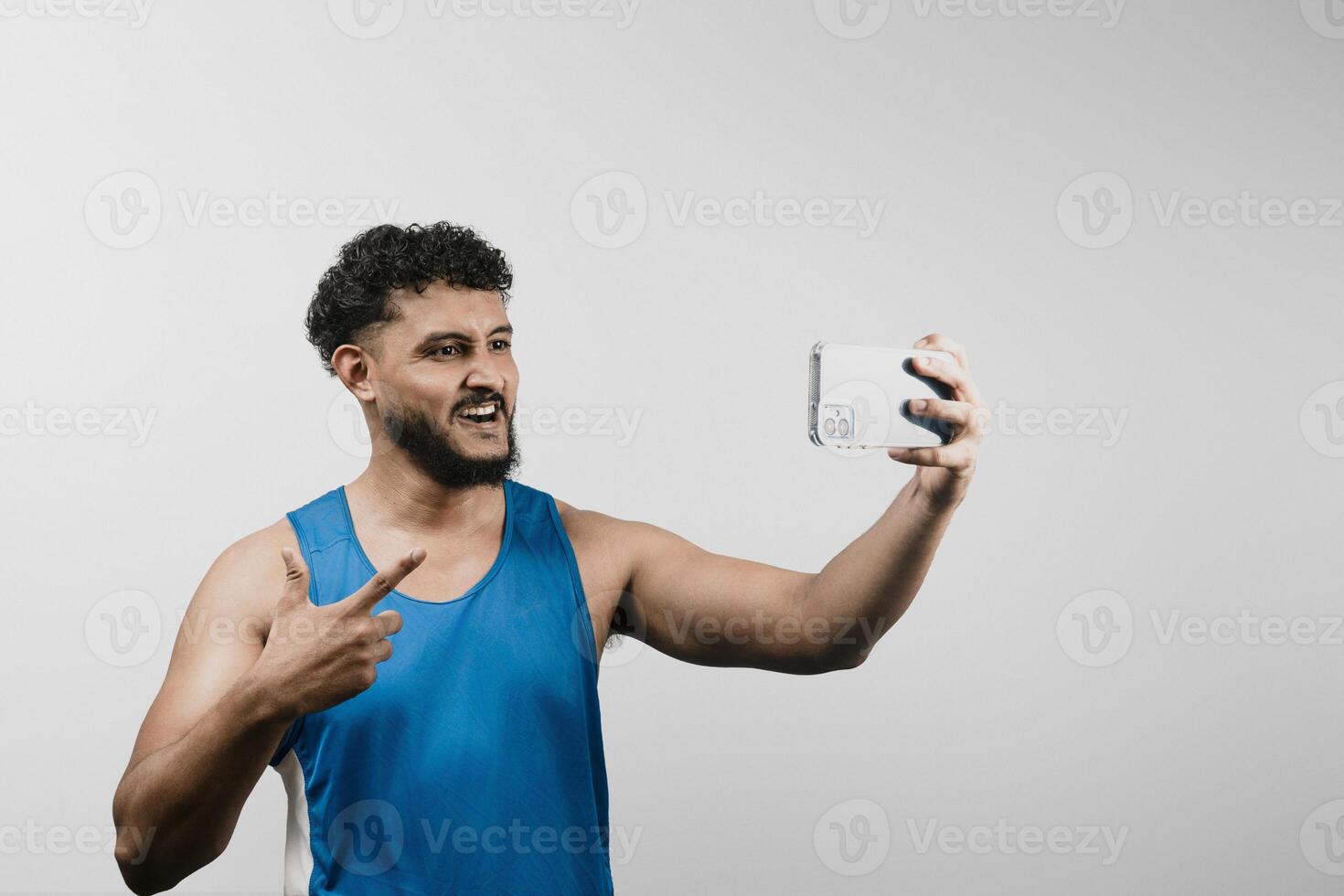 Young latino sportsman showing progress on call holding smartphone and pointing finger photo
