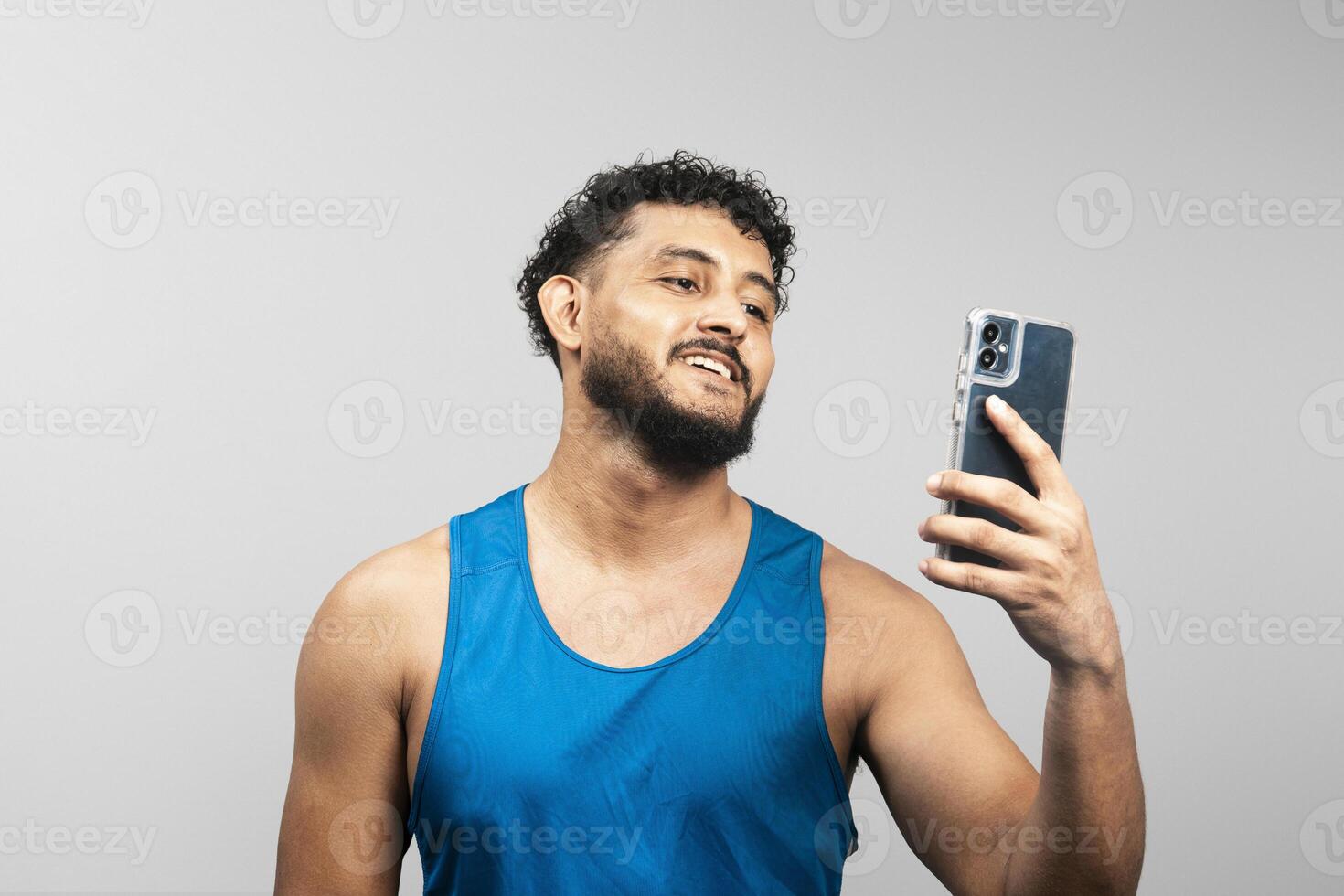 Smiling sportsman using smartphone app, checking progress of muscle growth photo
