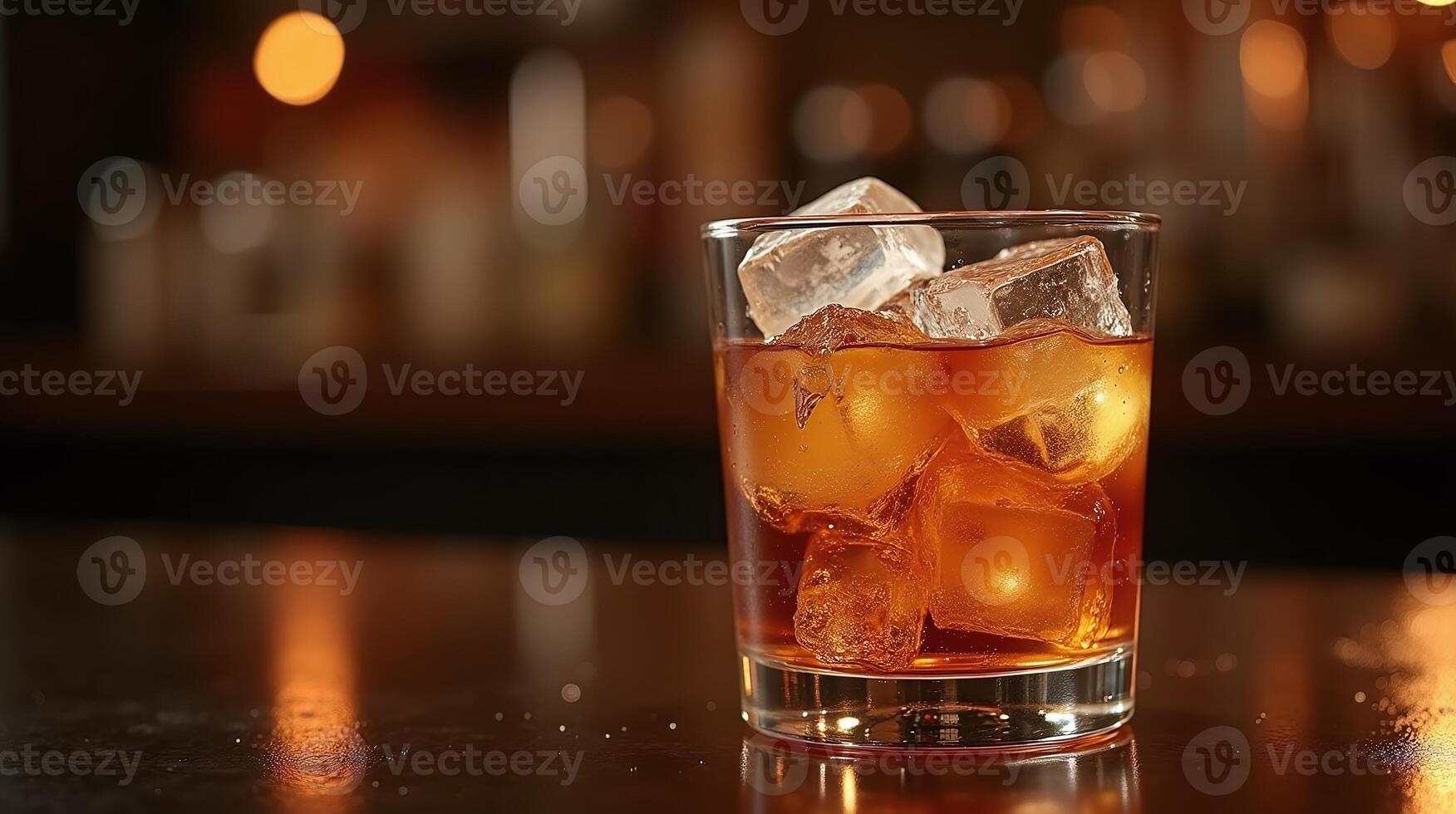 A glass of amber liquid with ice, set on a wooden bar. photo