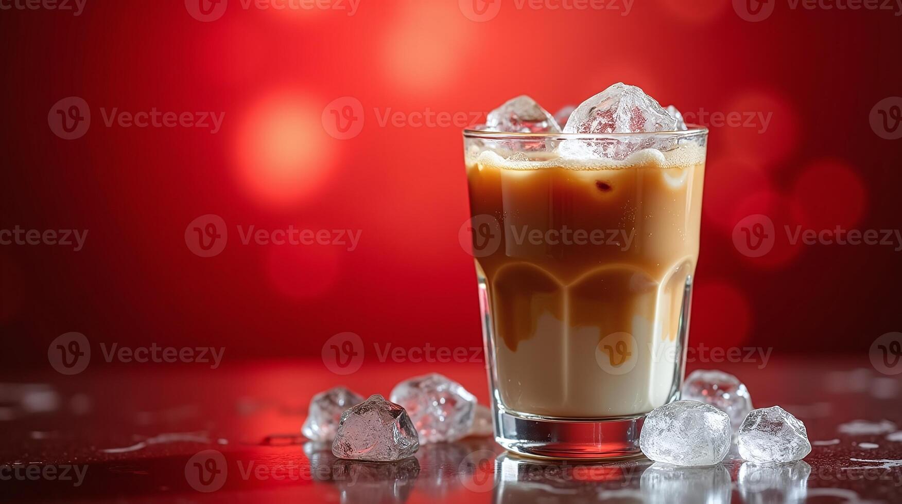 A glass of iced coffee with frothy milk and ice cubes, set against a vibrant red background. photo