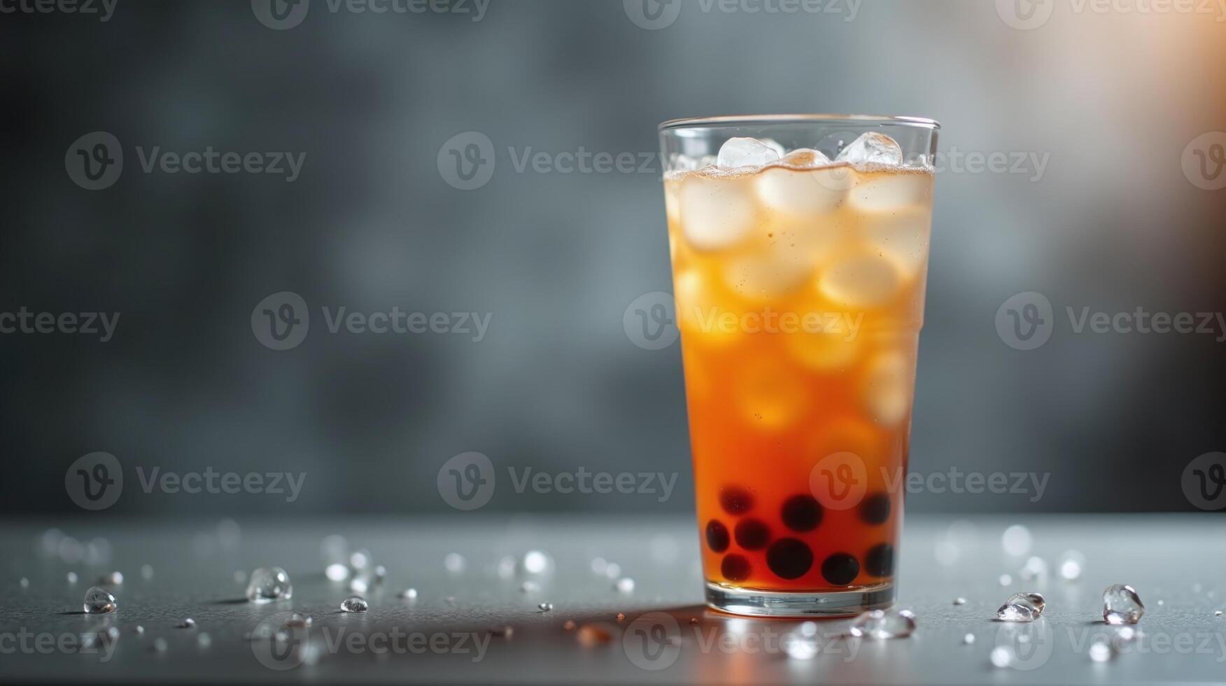 A glass filled with iced tea, bubbles, and ice cubes is set on a table. photo