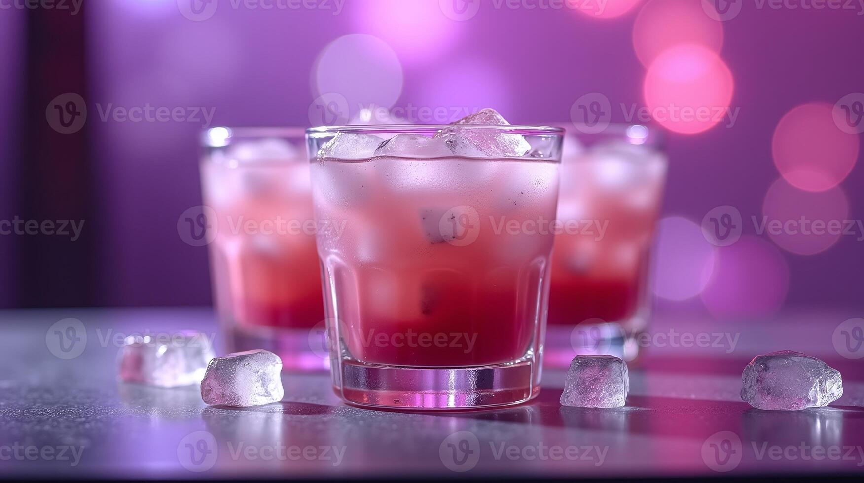 Three glasses of red beverage with ice, on a table against a blurred background. photo