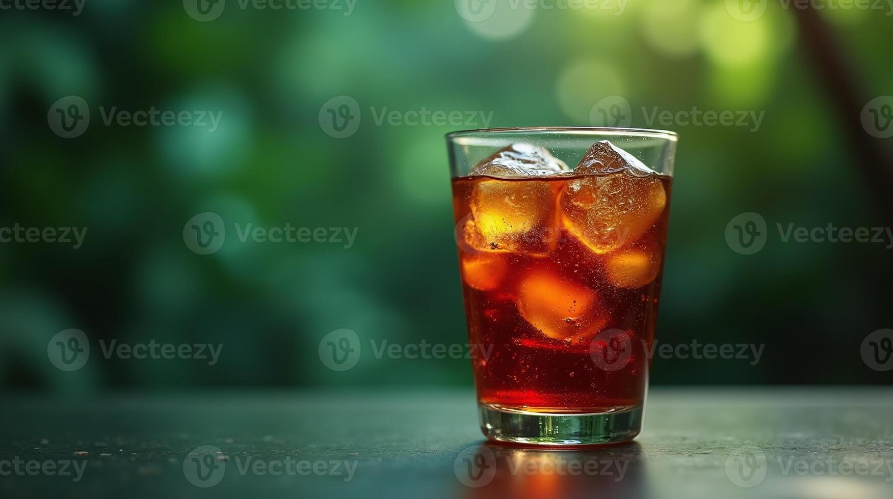 A glass of refreshing iced tea with ice cubes, set against a blurred green background. photo