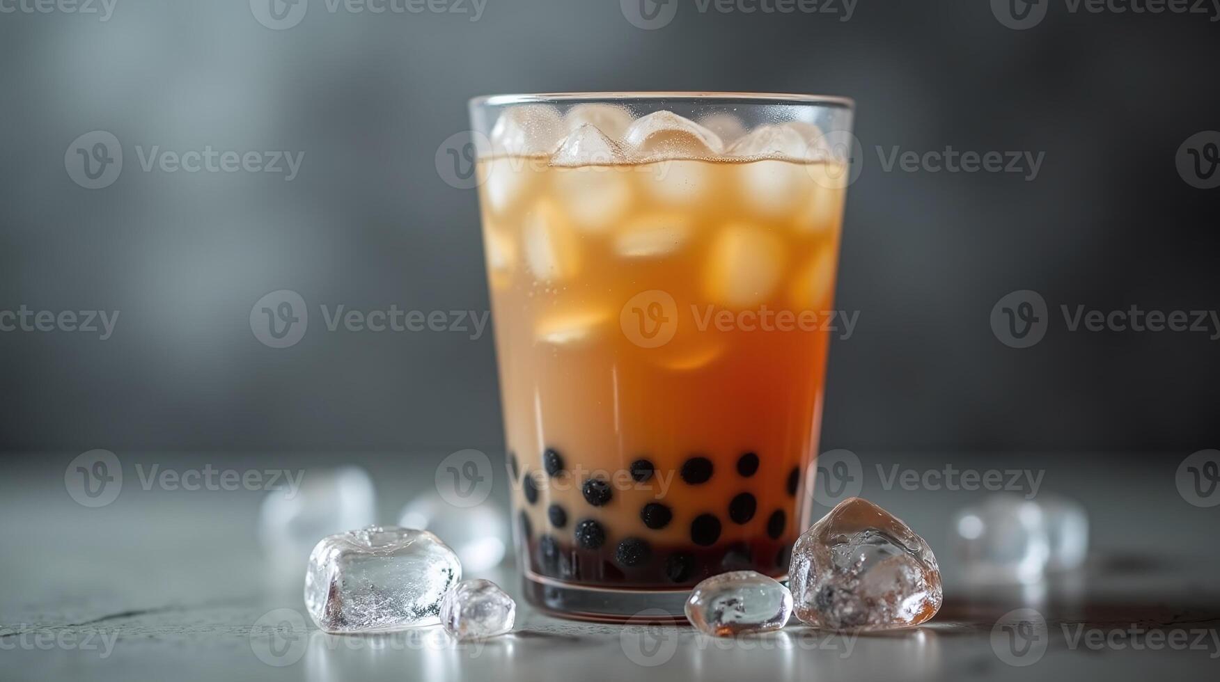 Frothy beverage with dark pearls floating in clear glass amidst dispersed ice cubes. photo