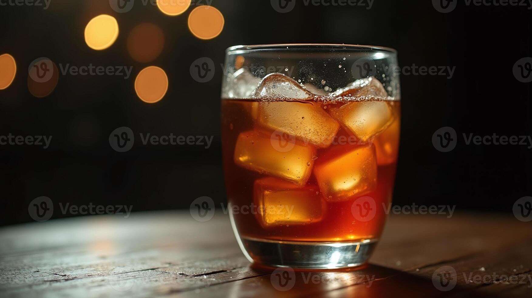 Glass with brown liquid and ice cubes on table. photo