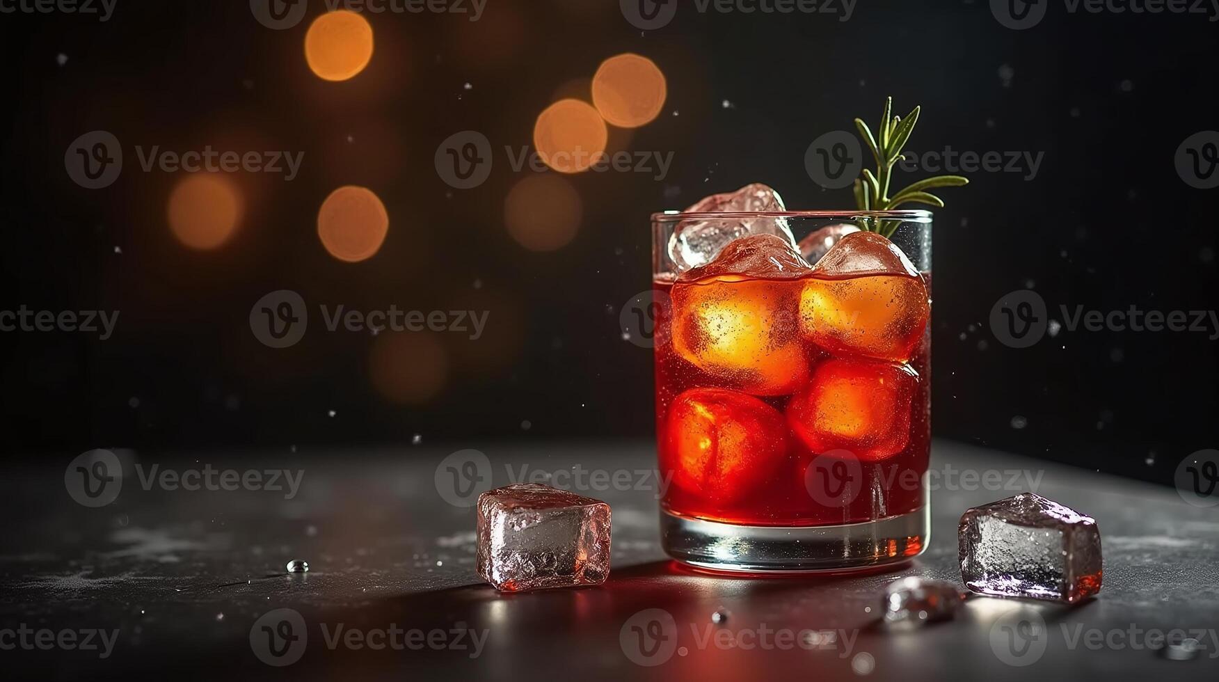 A vibrant beverage in a clear glass adorned with ice cubes and a sprig of rosemary against a dark, blurred background. photo