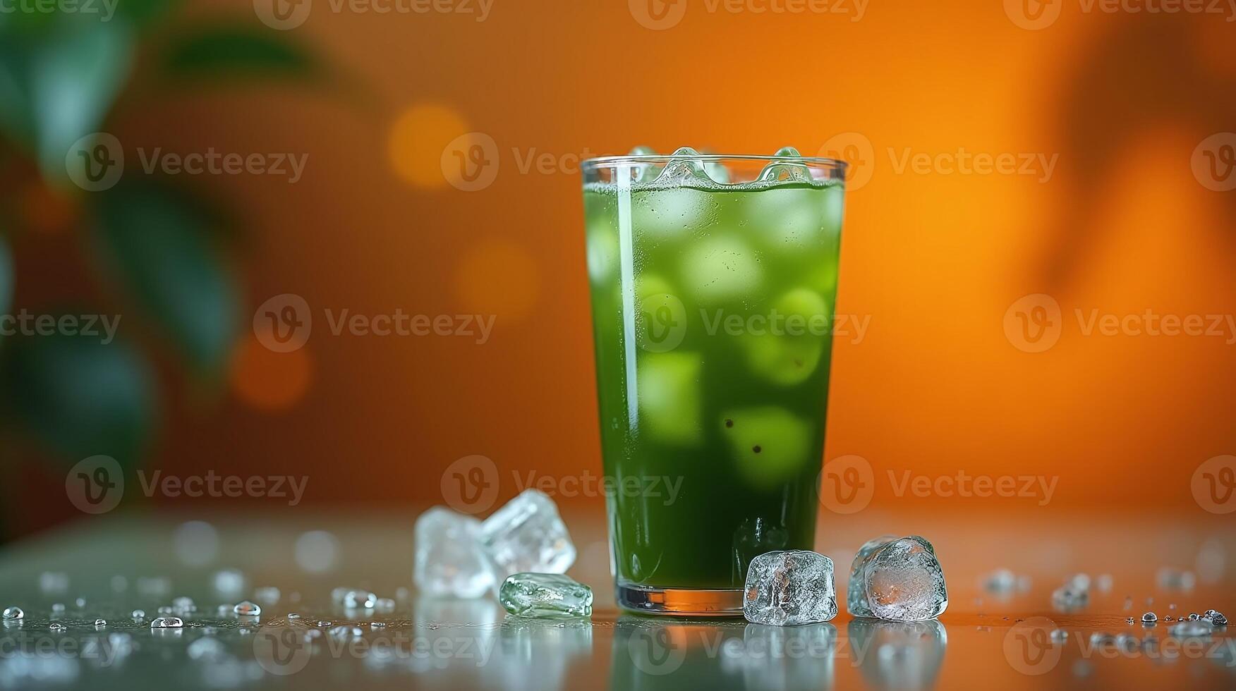 A refreshing glass of green beverage with ice cubes on a table. photo