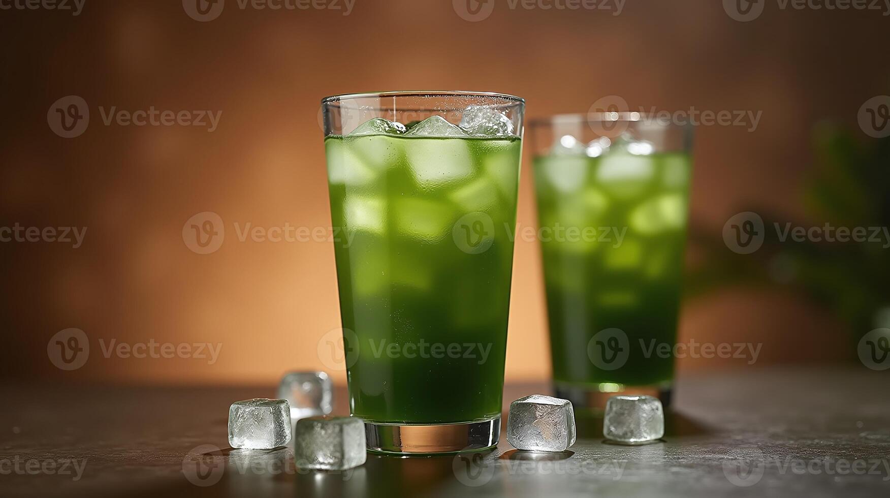 Two glasses filled with vibrant green drink, accompanied by ice cubes, set against a warm-toned backdrop. photo