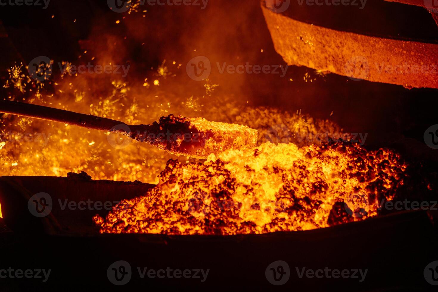 Removing slag from surface of hot iron in melting furnace, close up photo
