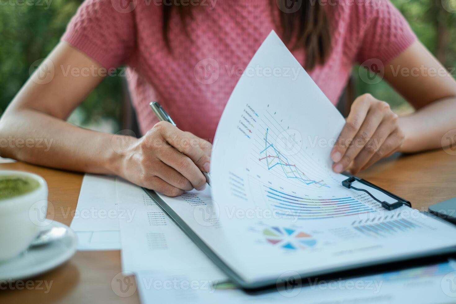 Close-up of a woman reviewing financial documents with graphs and charts, highlighting business analysis and strategic planning. photo