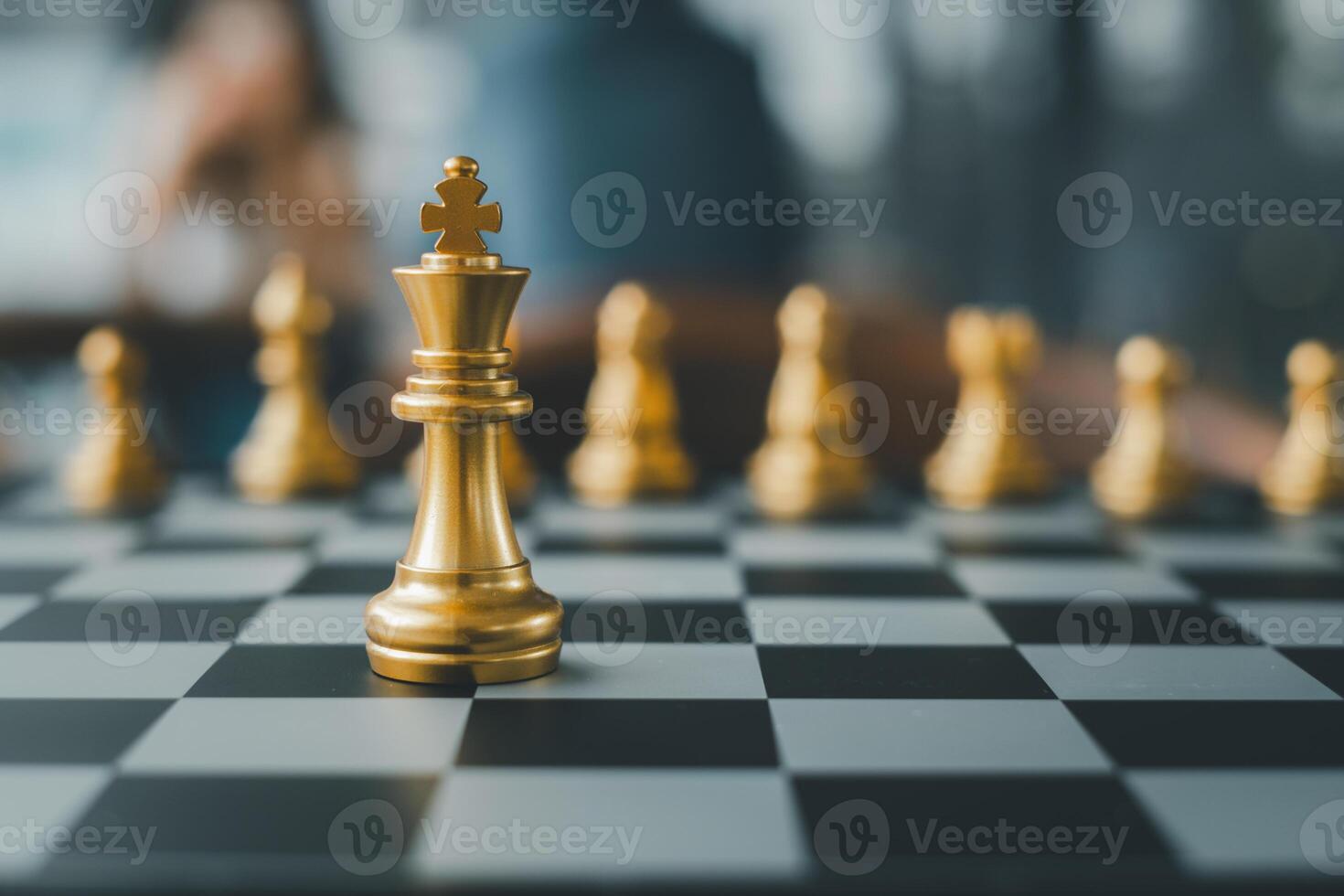 Close-up of golden chess pieces on a chessboard, highlighting the king in a strategic game setting. photo