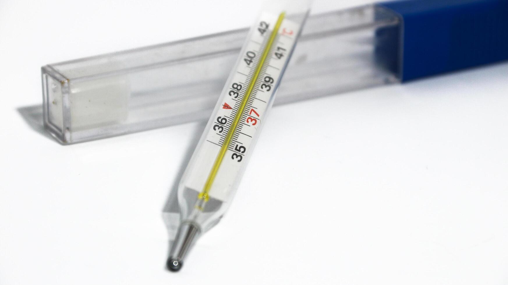 Close-up shot of clinical thermometer on white surface. Medical glass thermometer shows normal body temperature of 37 degrees Celsius photo