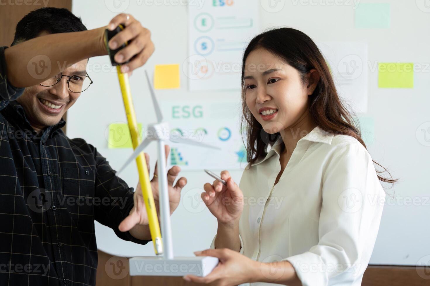 Sustainability and Engineering. Engineers measuring wind turbine models in a collaborative workspace. photo