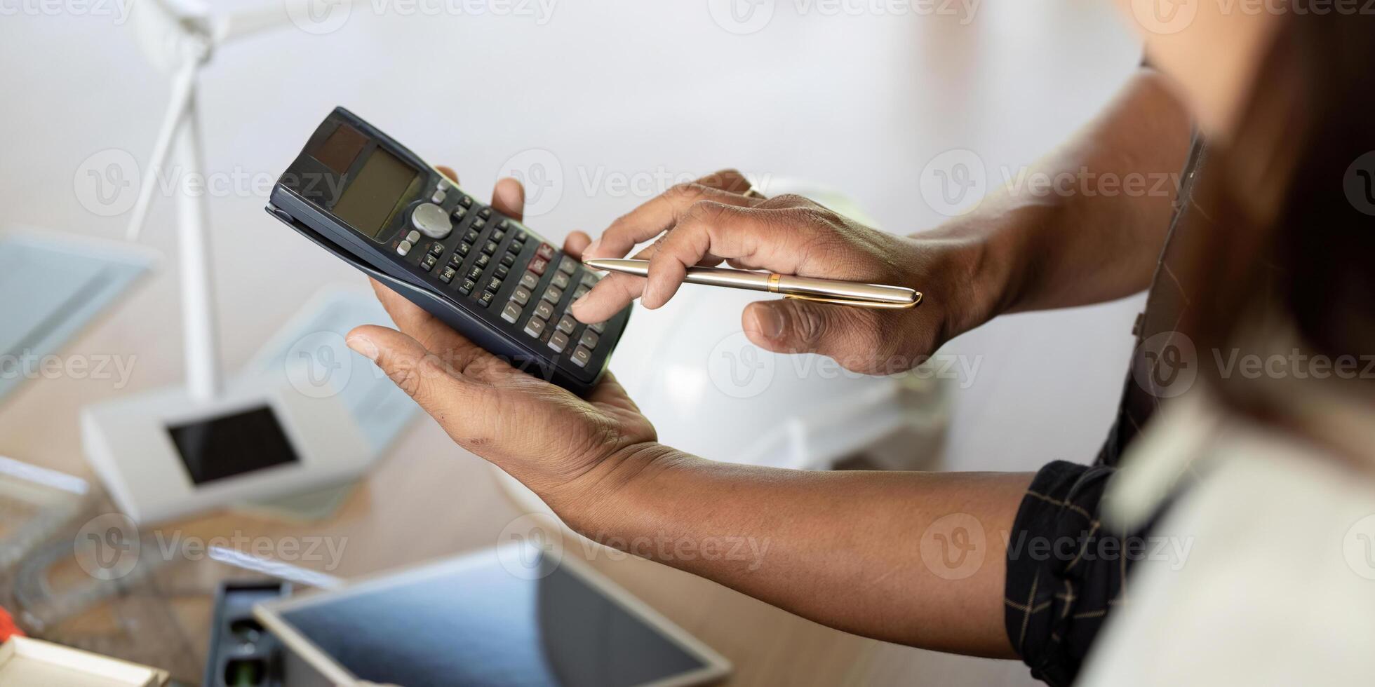 Sustainability and Engineering. Engineer using calculator for sustainable project analysis. photo