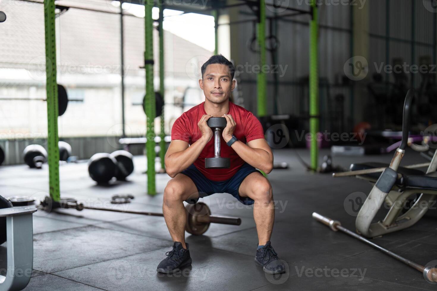 Wellness through Strength Training. Man performing squat with dumbbell in gym. photo