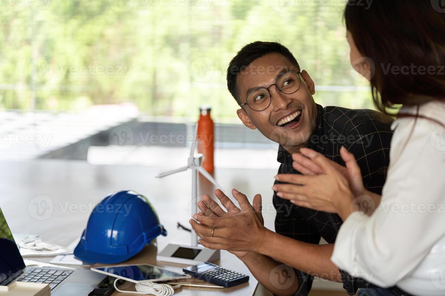 Sustainability and Teamwork. Engineer celebrating success with a colleague in a modern office. photo