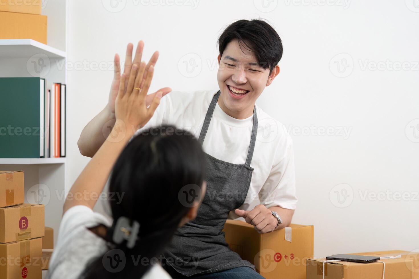 Couple collaborating in a business setup, sharing joyful moments while handling packages. photo