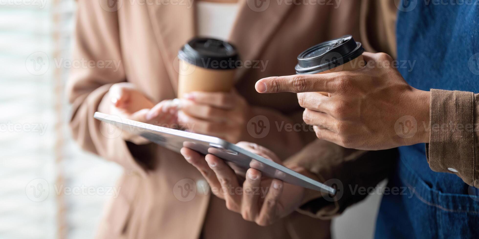 Collaboration and Coffee. Young professionals reviewing a project on a tablet while enjoying coffee. photo