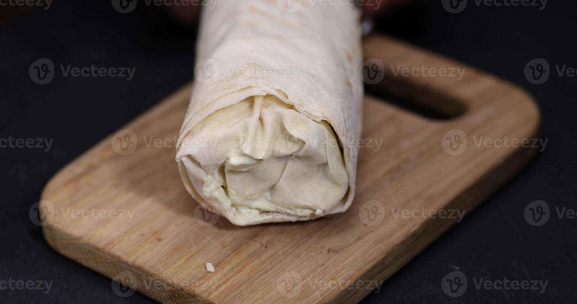 one shawarma made from thin wheat tortilla with meat with tomatoes and sauce, fast food made from various ingredients packed in foil photo