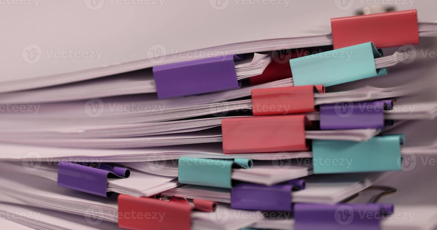 white sheets of paper are connected by multicolored metal clips, stacked sheets of paper for documents are joined together, sheets of paper is different in each clip photo