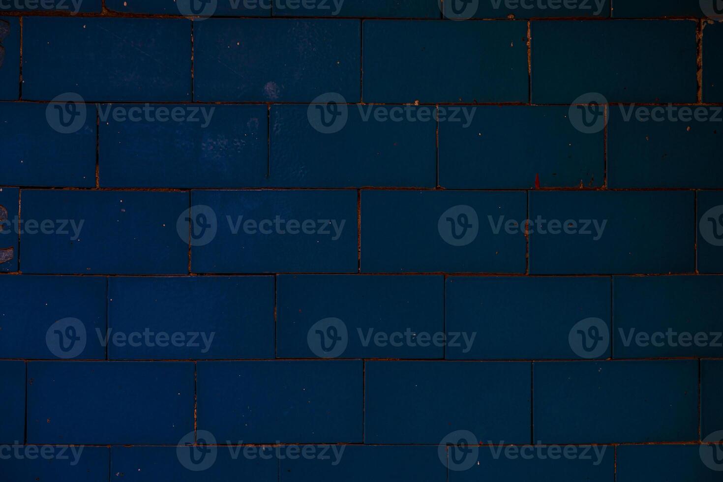 Close-up of a dark blue ceramic tiled wall with horizontal rectangular tiles and subtle surface wear, ideal for backgrounds and design textures. photo
