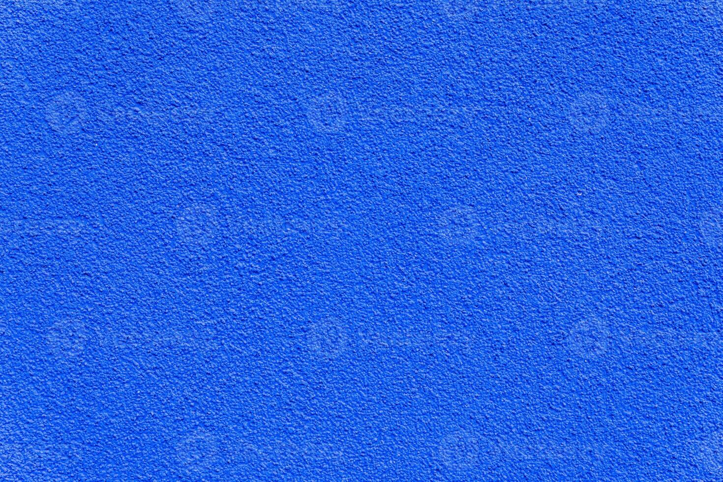 Close-up of a rough blue painted wall with subtle texture, ideal for backgrounds, design mockups, or architectural use. photo