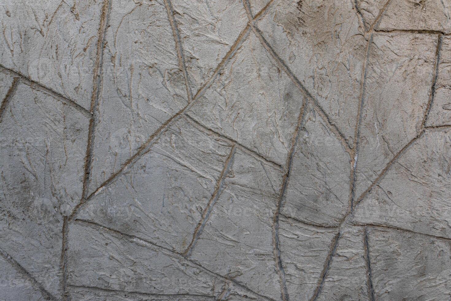 Detailed view of a gray plaster wall with geometric trowel patterns and rugged texture, suitable for architectural and design backgrounds. photo