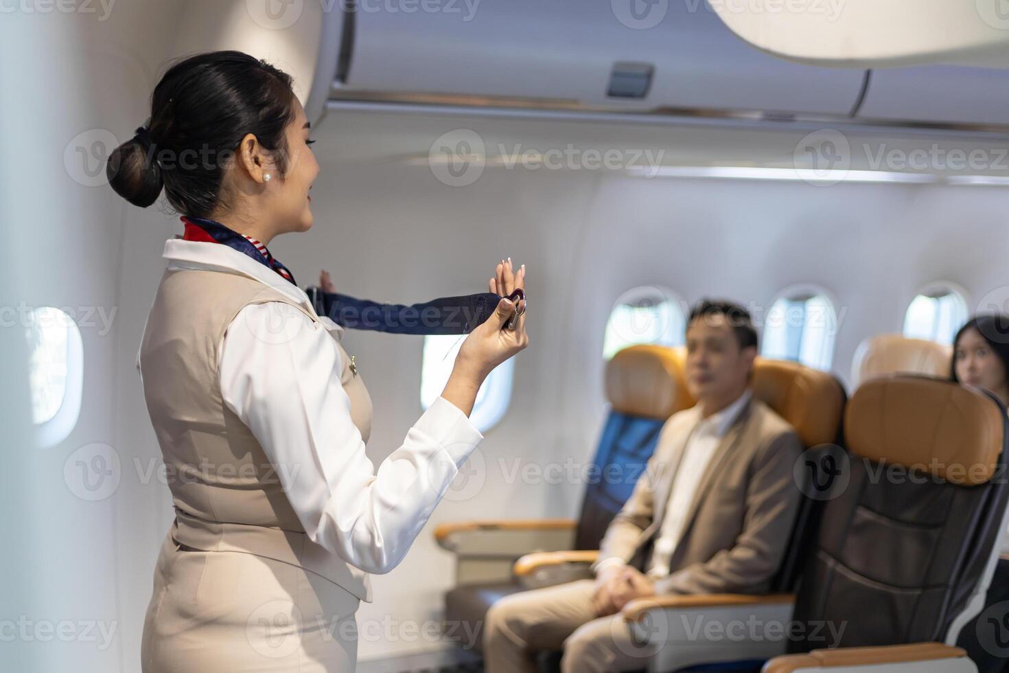 Asian flight attendant is demonstrating safety procedure using seat belt before taking off in the airplane for cabin crew and airline business usage photo