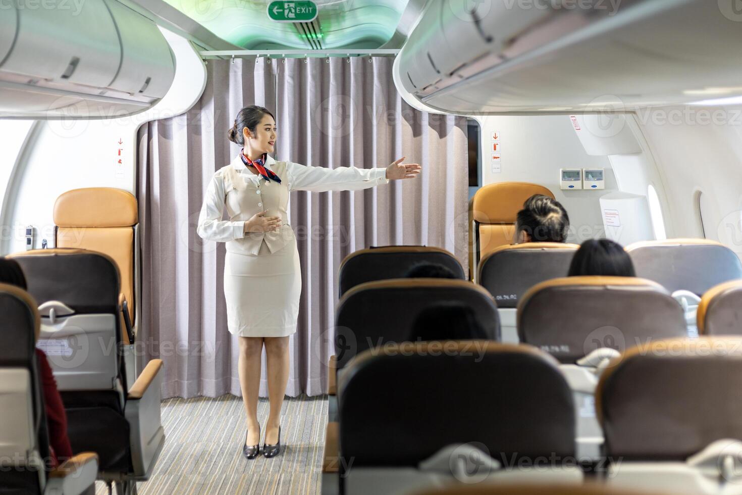 Asian flight attendant demonstrating safety procedure showing emergency exit before taking off in the airplane for cabin crew and airline business photo