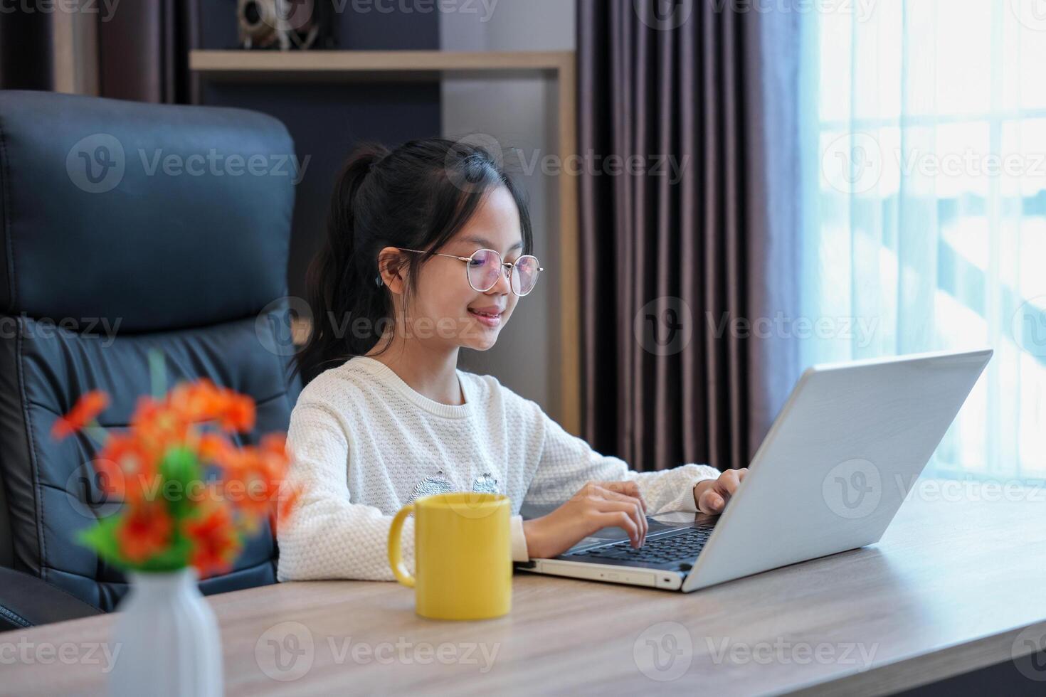 Young asian schoolgirl doing class homework assignment at home using laptop computer for education and study concept photo