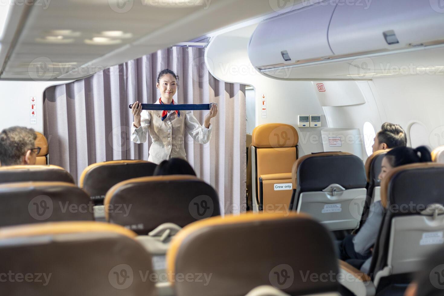 Asian flight attendant demonstrating safety procedure using seat belt before taking off in the airplane for cabin crew and airline business usage photo