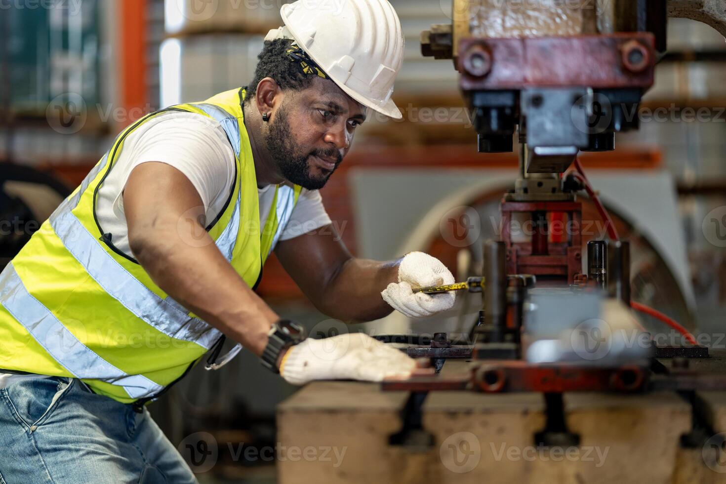 African American industrial worker is fixing hydraulic power press machine to make metal and steel part while working inside the metal sheet galvanized roof factory for safety industry photo