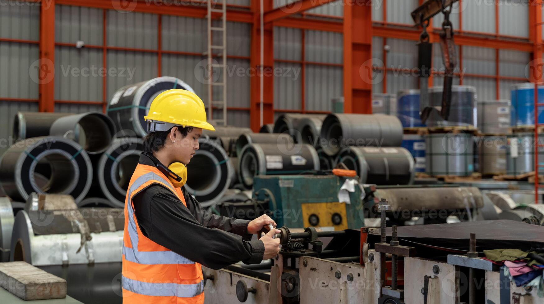 Asian industrial worker is checking the setup value of metal sheet roll forming machine inside the roof factory for safety industry construction usage photo