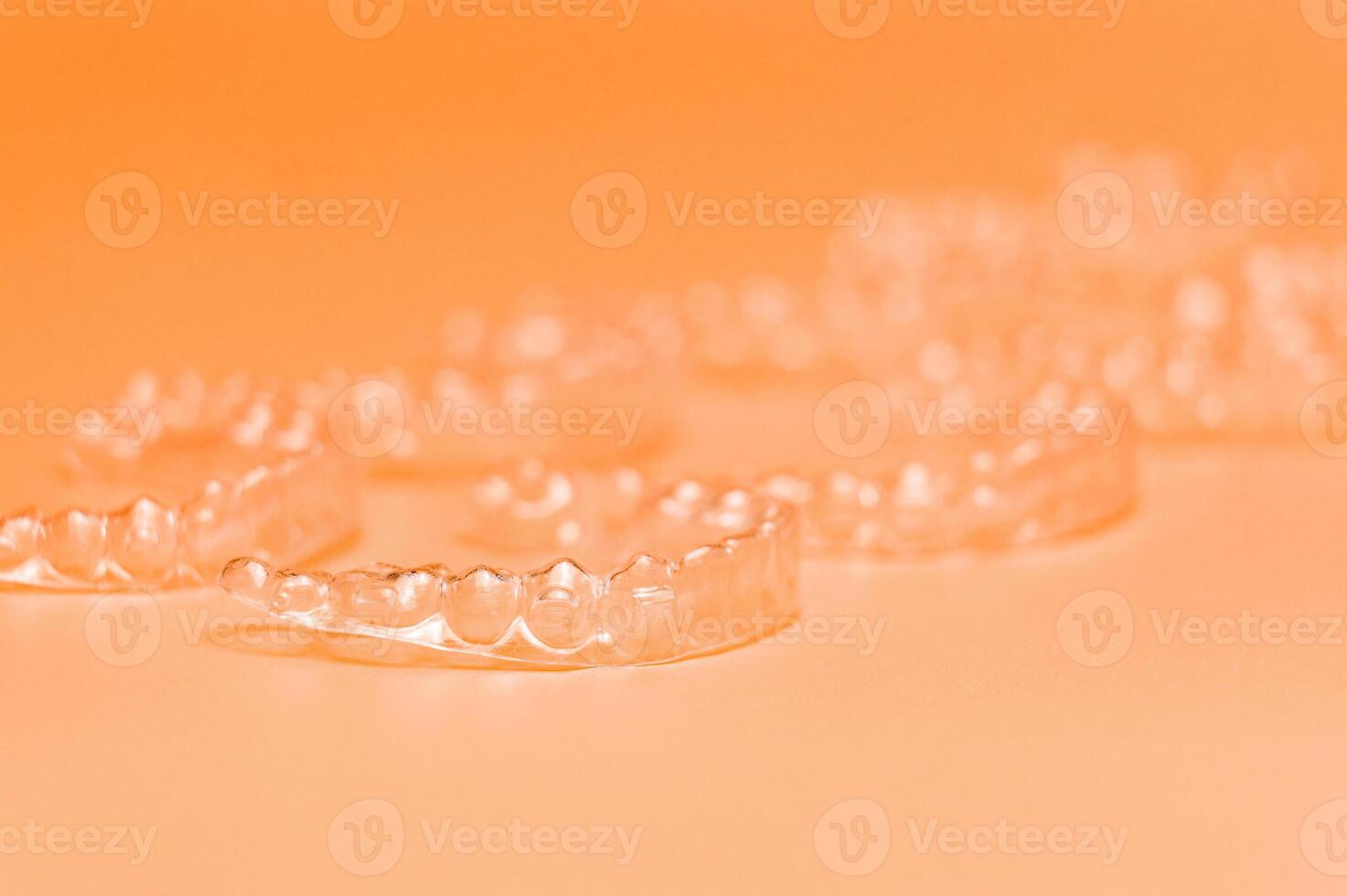 Orthodontic silicone aligner background. Advertisement of invisible braces retainer. Medical website concept. Pros and cons of aligners. peach saturated background photo