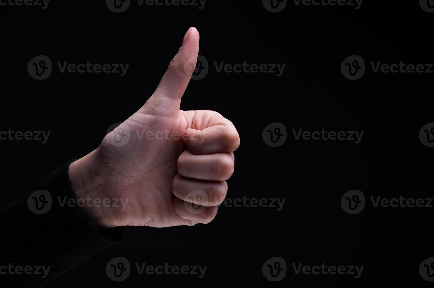 Hand of man showing thumb up gesture on black background. Sign fingers Like photo