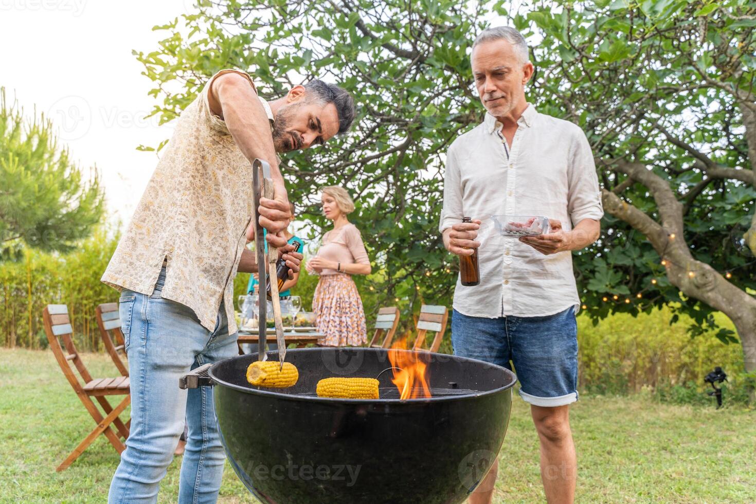 Multiethnic middle-aged people cooking with the barbecue smiling happy and laughing together photo
