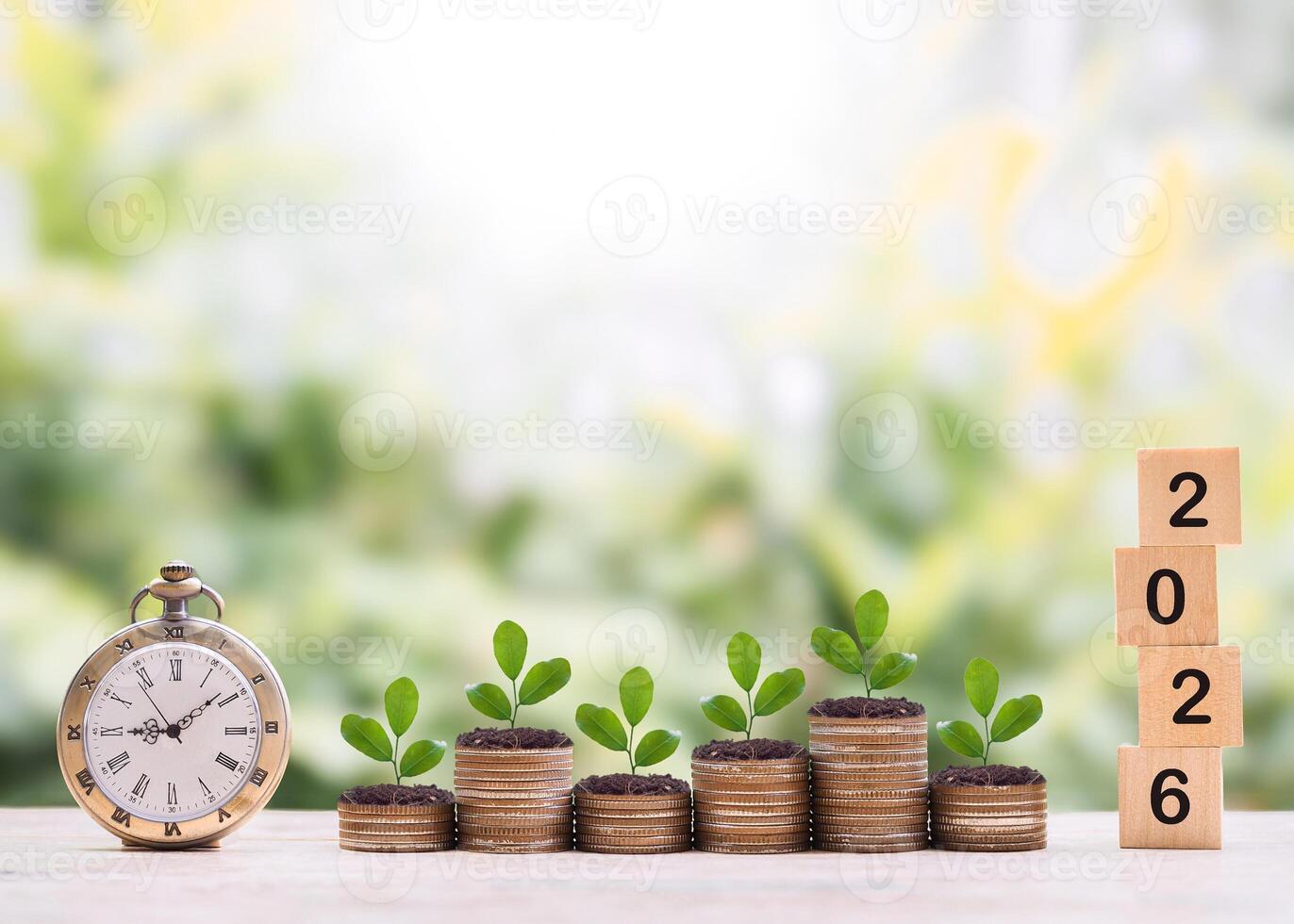 Vintage watch, Wooden blocks with the number 2026 and plants growing up on stack of coins. The concept of saving money for manage time to success business in year 2026 photo