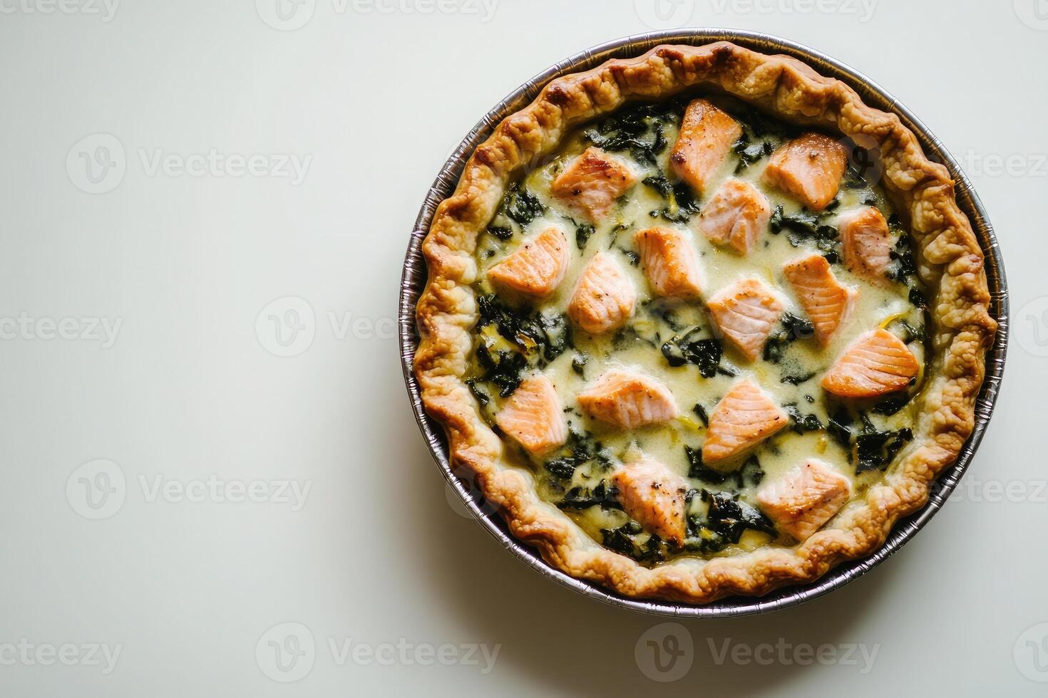 Perfectly styled open salmon pie with wilted spinach and creamy lemon filling on a clean white background and soft natural lighting photo