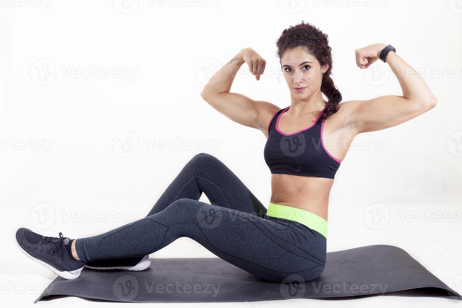 beautiful young sportswoman sitting on mat doing gymnastics isolated on white background photo