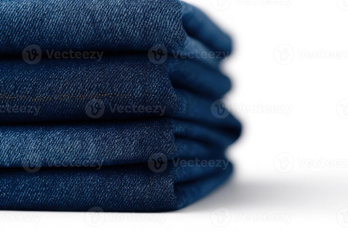 Dark blue jeans are neatly folded in a stack, highlighting their rich color and smooth texture. They are perfect for casual outfits and fashionable styles all year round. photo