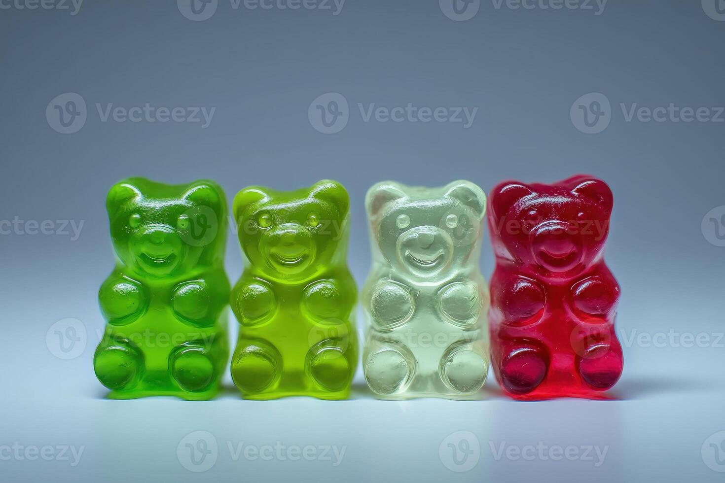 Four gummy bear candies in vibrant colors of green, yellow, and red are aligned on a smooth surface. The bright hues highlight the playful and fun nature of these popular sweets. photo