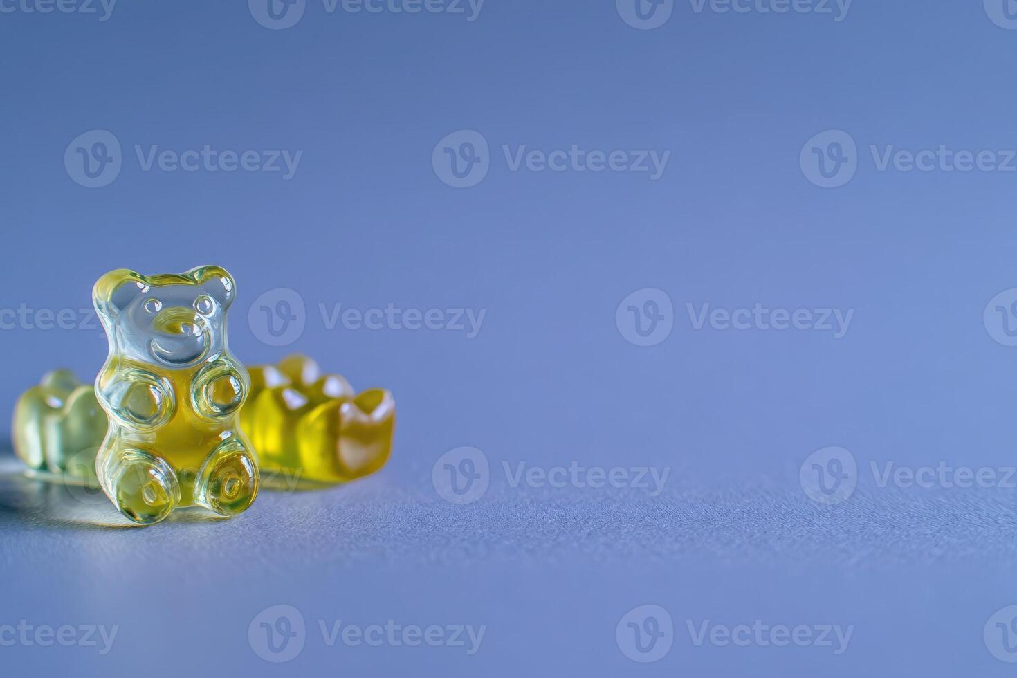 A vibrant gummy bear and other candy shapes sit on a smooth, light surface. The playful arrangement highlights their different colors and textures, inviting a sense of fun and indulgence. photo