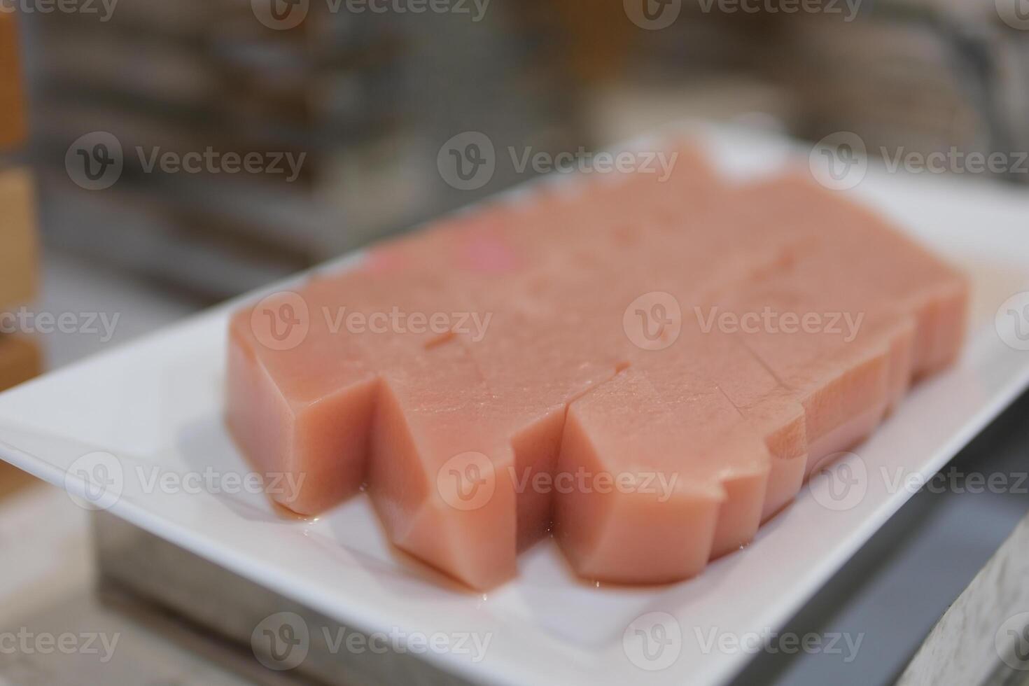 No baked raspberry cheesecake or raspberry cream mousse cake with jelly and fresh berries on top on a white plate on a gray concrete background. Summer cake photo