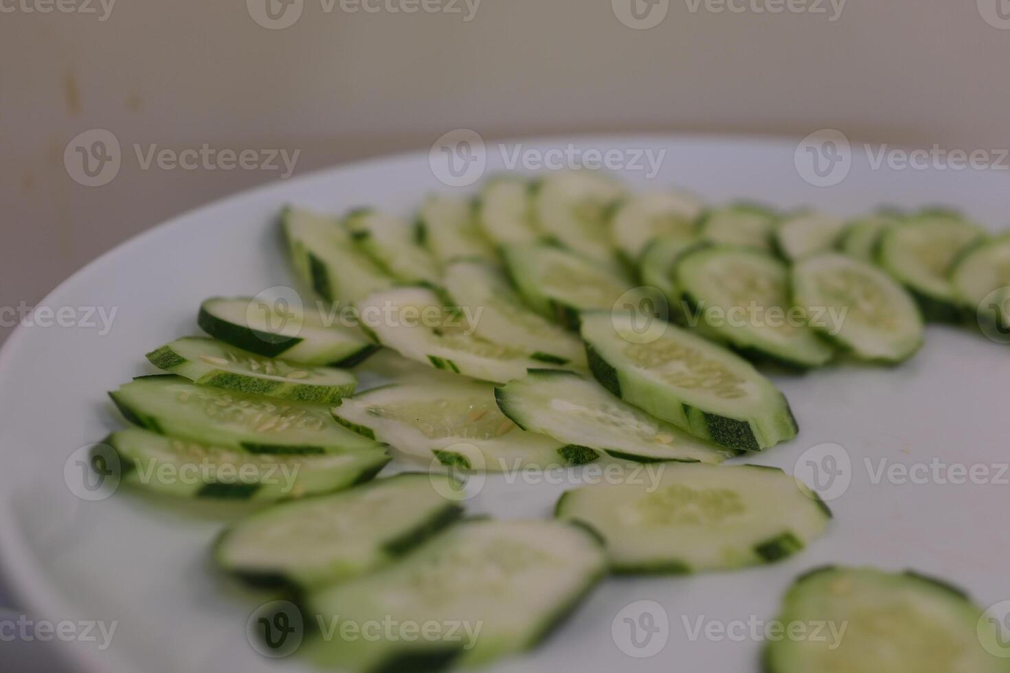 sliced cucumbers rotating on black plate, centered with strong reflection photo
