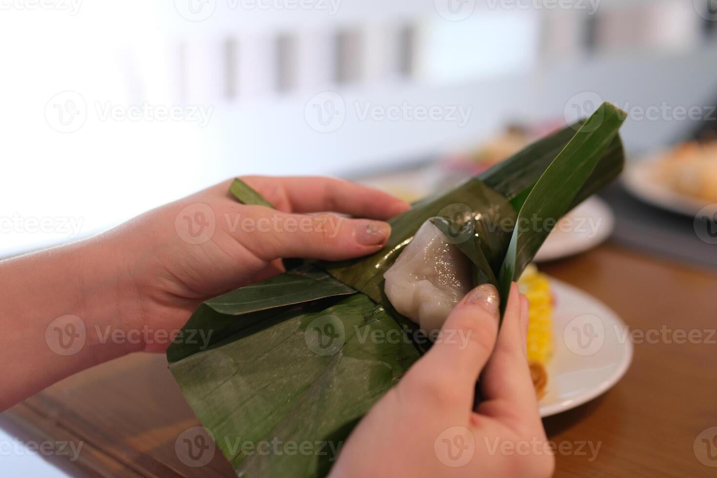 Traditional cake wrapped in banana leaves shaped like a cone, called Mendut cake, filled with grated coconut photo