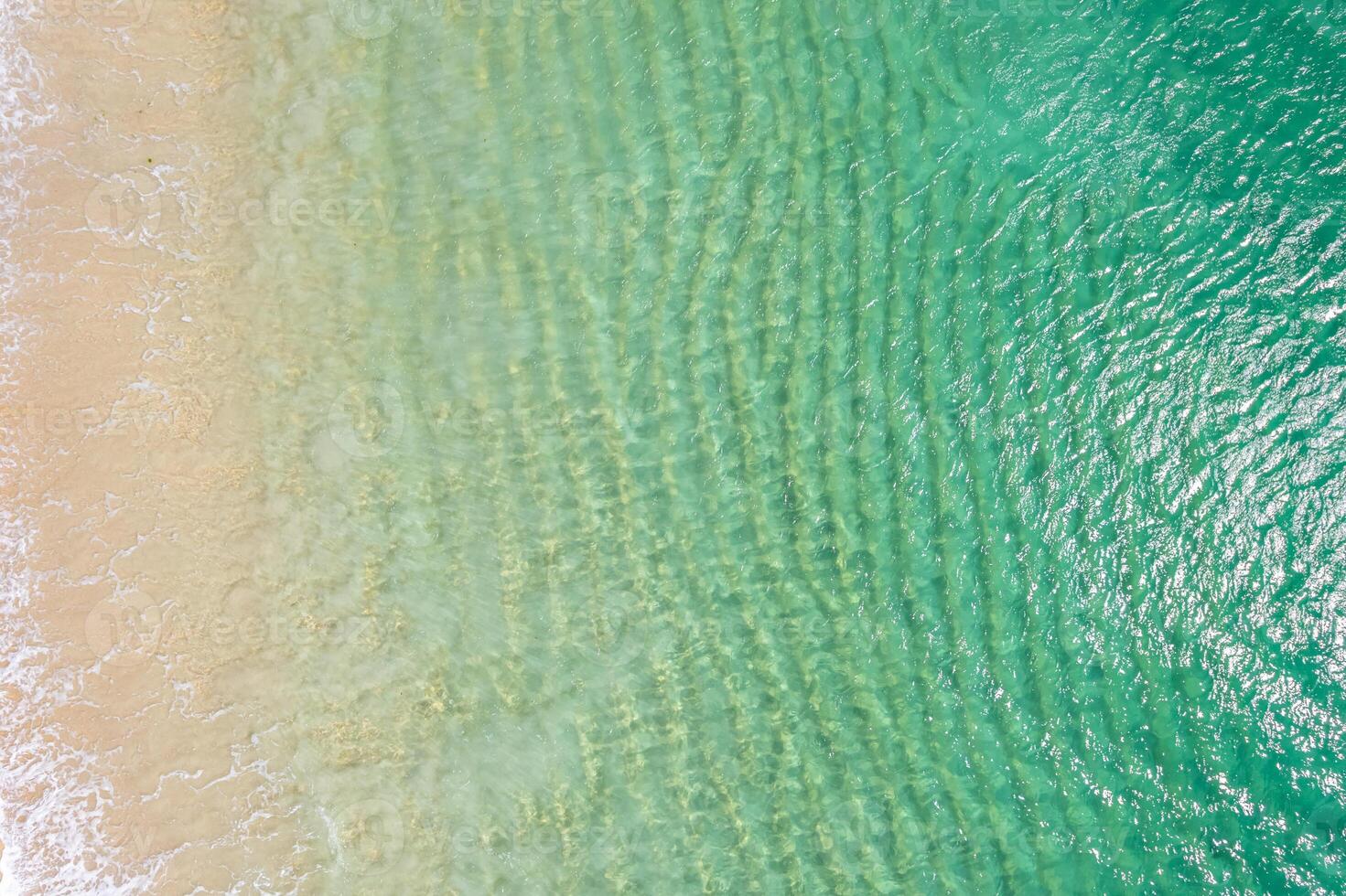 shore of a beach with pristine turquoise waters and golden sand. Overhead aerial view with drone, background for tropical summer concept. photo
