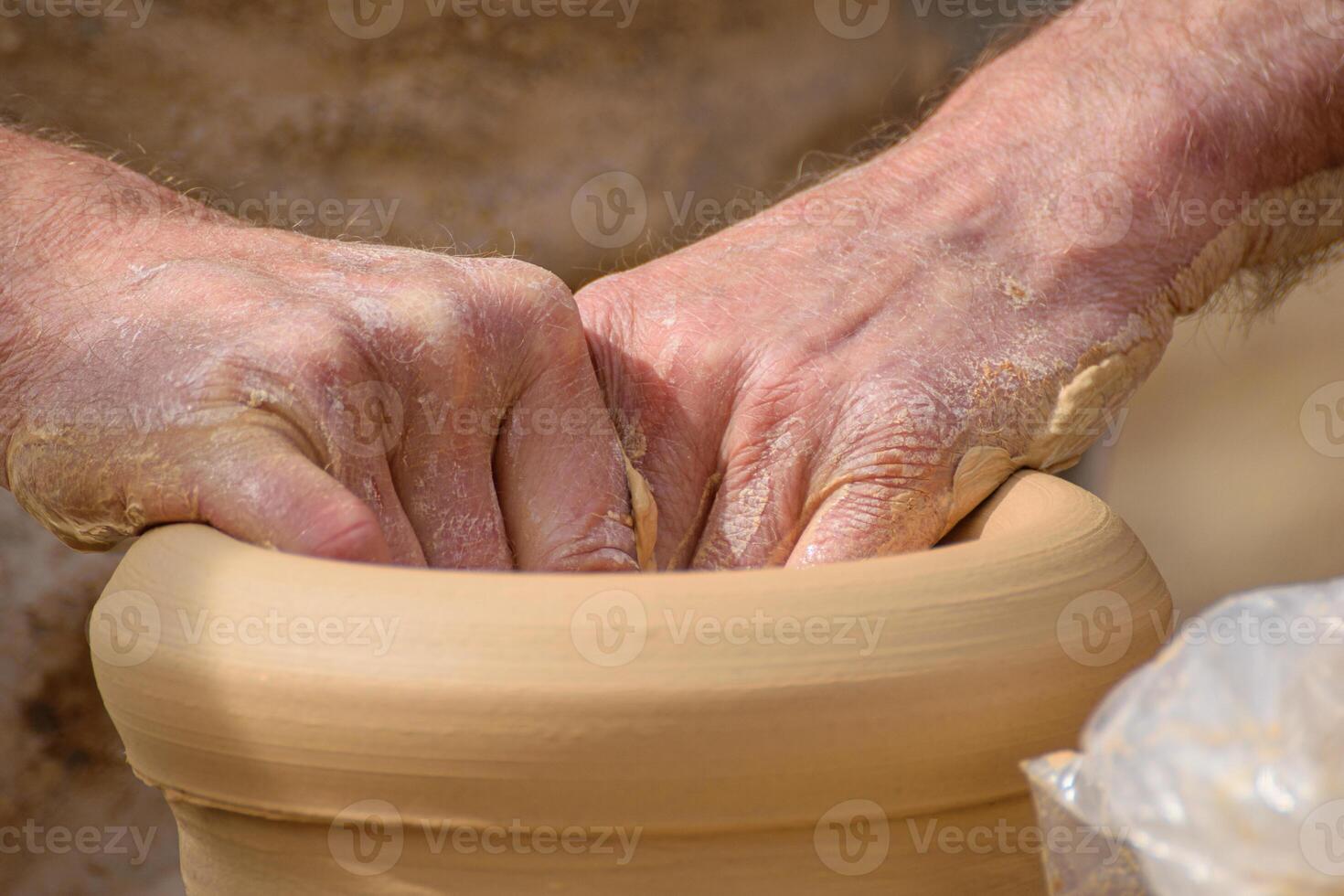 hands of an artisan potter molding a clay pot on a potter's wheel in a pottery kiln. photo