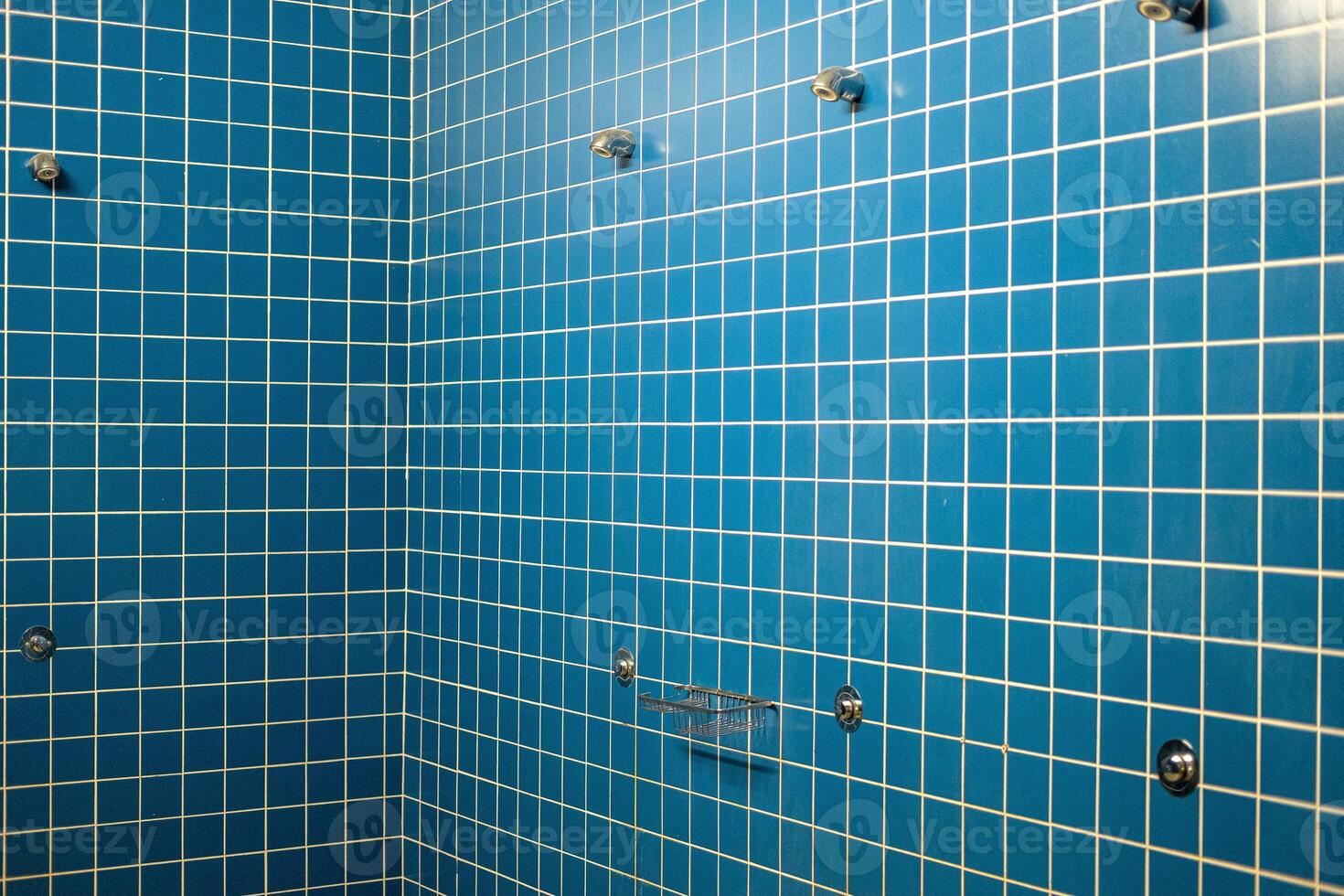 empty shower cubicle interior with white grout lines in a gym photo